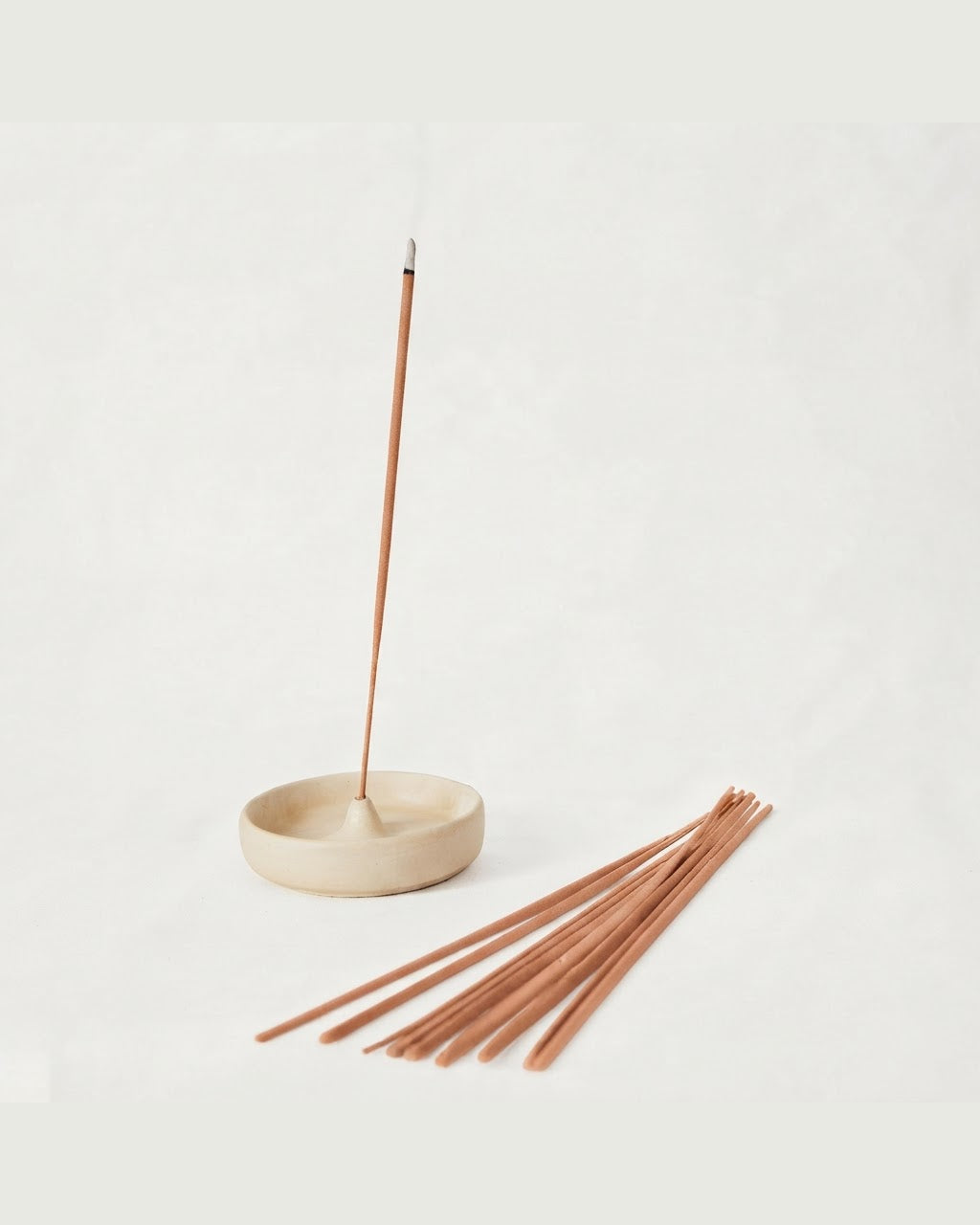 Sandalwood incense stick burning in a concrete holder — Sage Botanicals Co